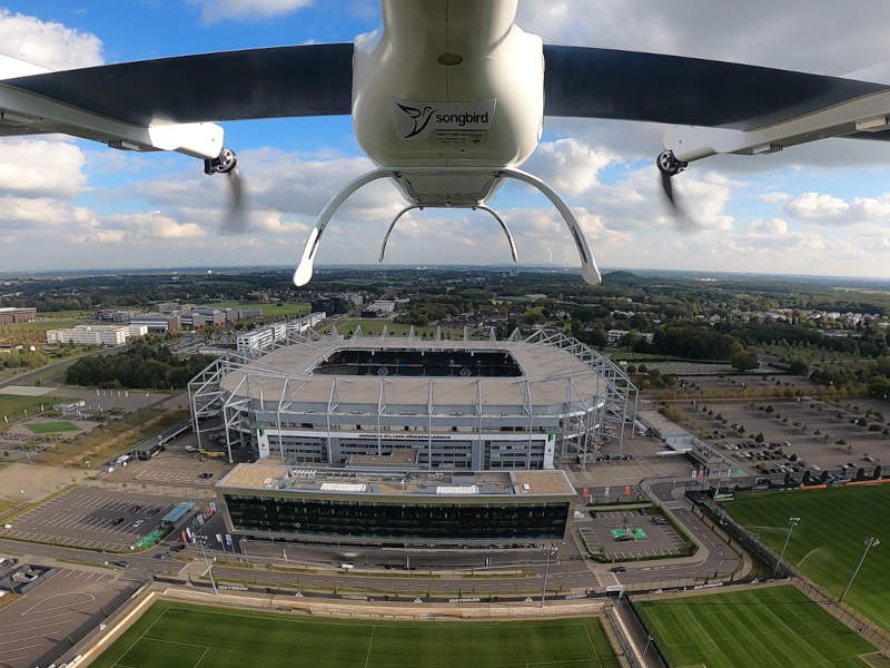 Songbird UAV im Flug mit Fußballstadion im Hintergrund